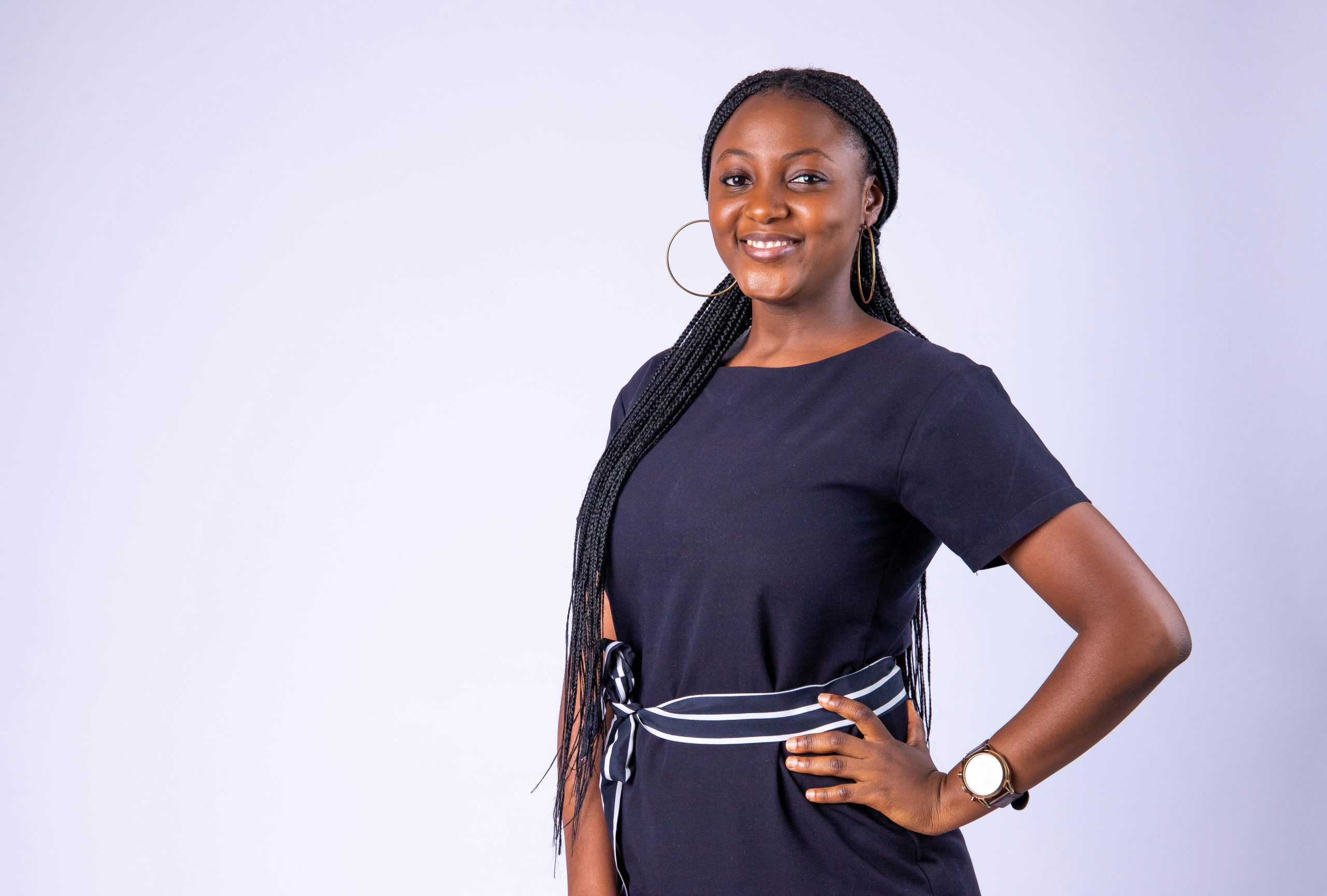Portrait of a confident African woman smiling with hand on waist in a studio setting.