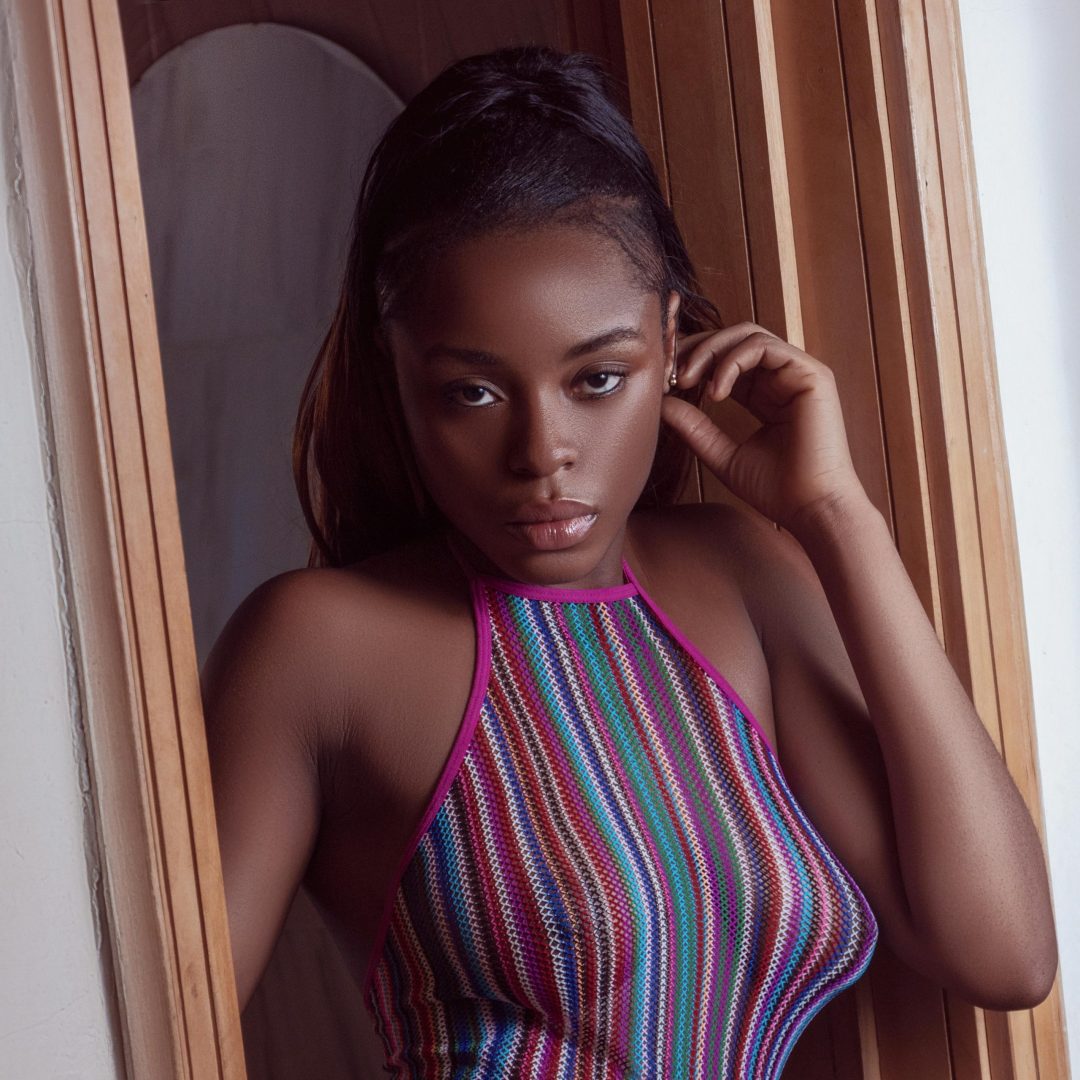Studio portrait of a stylish young woman in a colorful outfit, posing confidently.